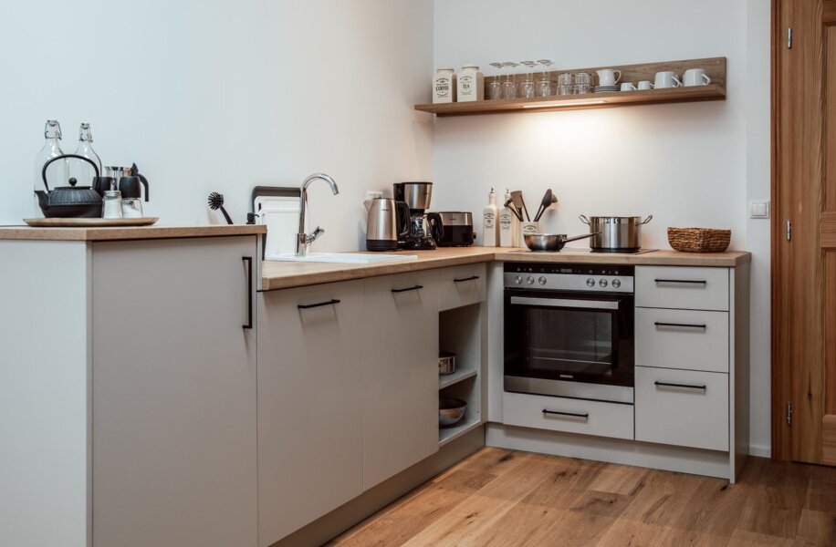 Voll ausgestattete Küche in einem the salt Apartment mit Holzarbeitsplatten und eingebauten Geräten.