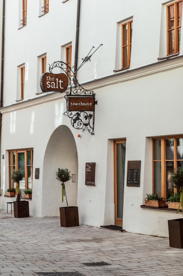 Fassade des the salt townhouse mit dekorativem Schild und Pflanzen in Töpfen, einladende Atmosphäre in einer gepflasterten Gasse.
