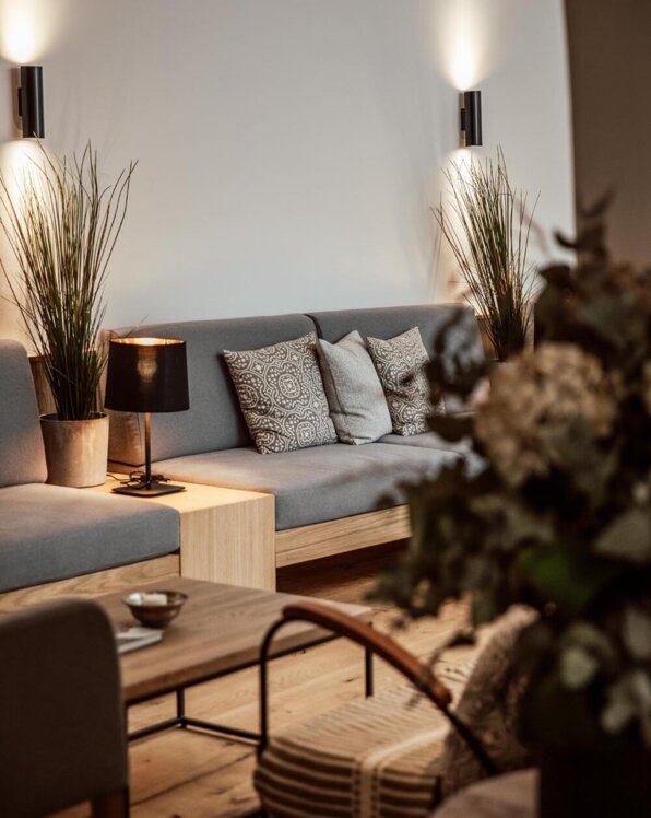Gemütlicher Lounge-Bereich mit grauem Sofa, dekorativen Kissen, Pflanzen und stilvoller Beleuchtung im the salt townhouse. 