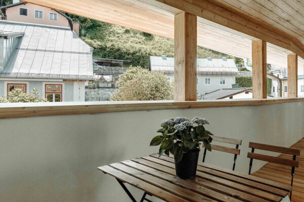 Großer, offener Holzbalkon mit Tisch und Stühlen im Galerie-Apartment von the salt Hallein.
