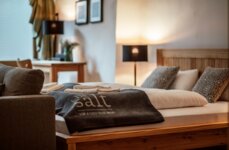 Gemütliches Schlafzimmer mit Holzbettrahmen, weichen Kissen und Decken im the salt. Warmes Licht und stilvolle Dekoration schaffen eine einladende Atmosphäre.