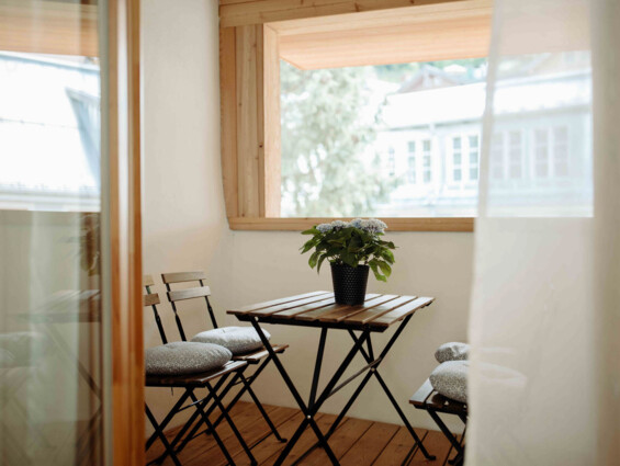 Balkon eines Apartments in Hallein bei Salzburg, ausgestattet mit Holzmöbeln und Blumendekor.