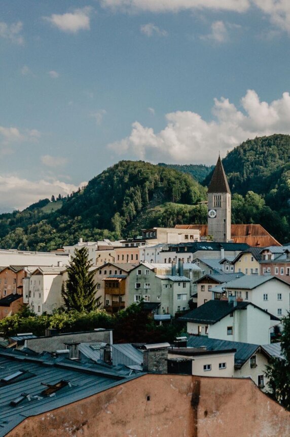 Blick auf die malerische Stadt Hallein mit historischen Gebäuden und bewaldeten Hügeln im Hintergrund.