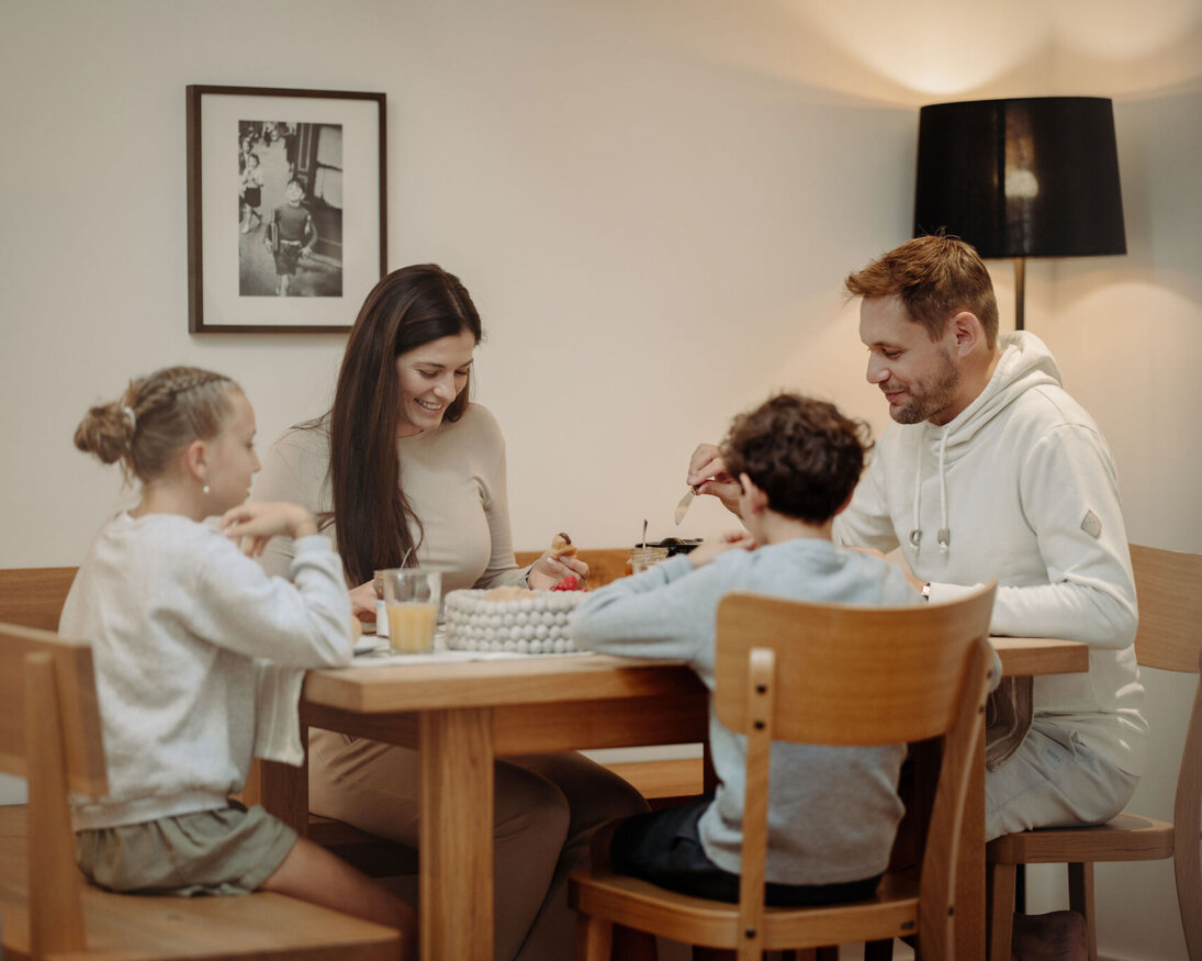 Familie genießt eine Mahlzeit am Holztisch in einem gemütlichen Apartment von the salt in Hallein.