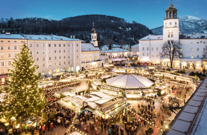 Abendstimmung am Salzburger Christkindlmarkt am Residenzplatz: Lichterglanz, großer Weihnachtsbaum und viele Stände vor historischer Kulisse.
