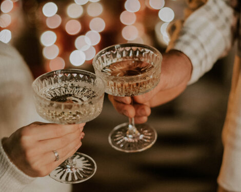 Zwei Personen stoßen mit Sektgläsern an, im Hintergrund Lichter.