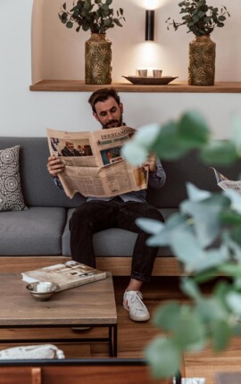 Ein Mann liest eine Zeitung im Loungebereich des the salt townhouse Boutiquehotels.