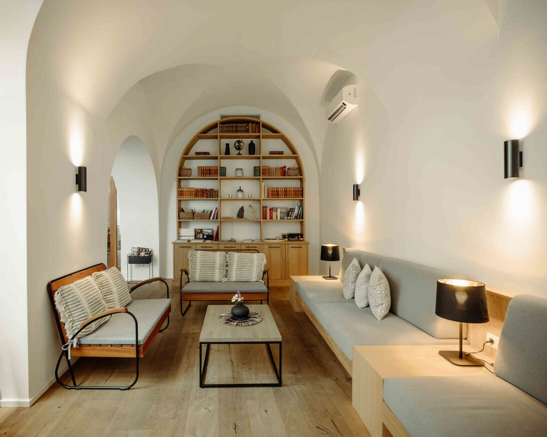 Sitzbereich im the salt townhouse mit gewölbter Decke, modernen Möbeln, Regalen und sanfter Beleuchtung.