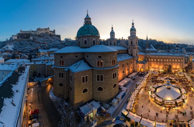 Winterlicher Panoramablick auf Salzburg mit Dom und Festung Hohensalzburg; stimmungsvoller Christkindlmarkt am Domplatz zur Dämmerung.
