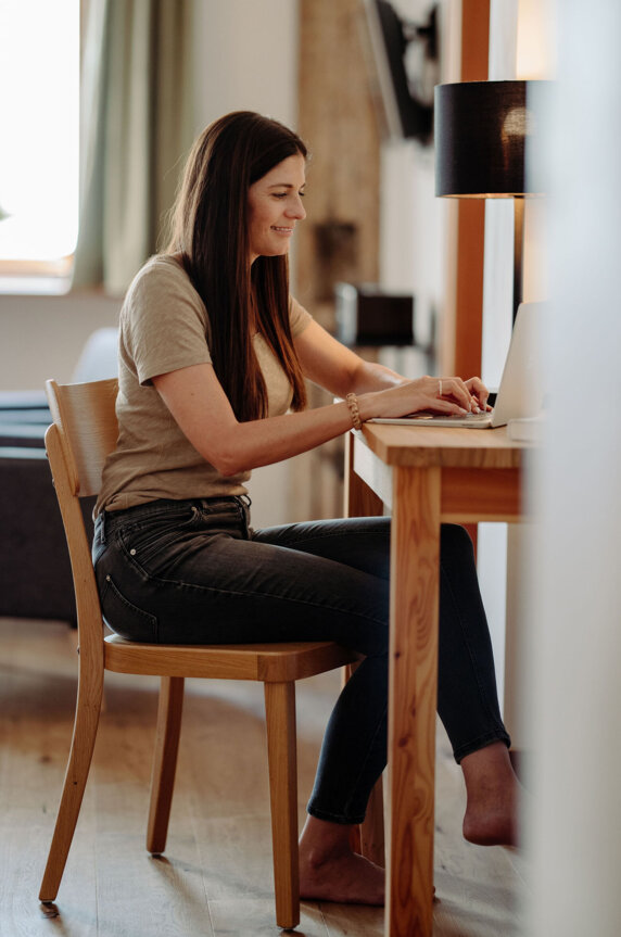 Guest working on a laptop at a wooden desk in a bright, cozy apartment.
